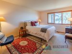 The first Queen bedroom is cozy with the seating area and rug.